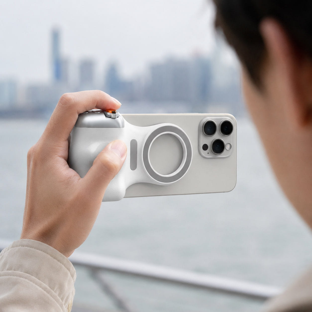 Close-up of a person holding the Luminomo Capture magnetic camera grip attached to a smartphone for comfortable handheld filming.