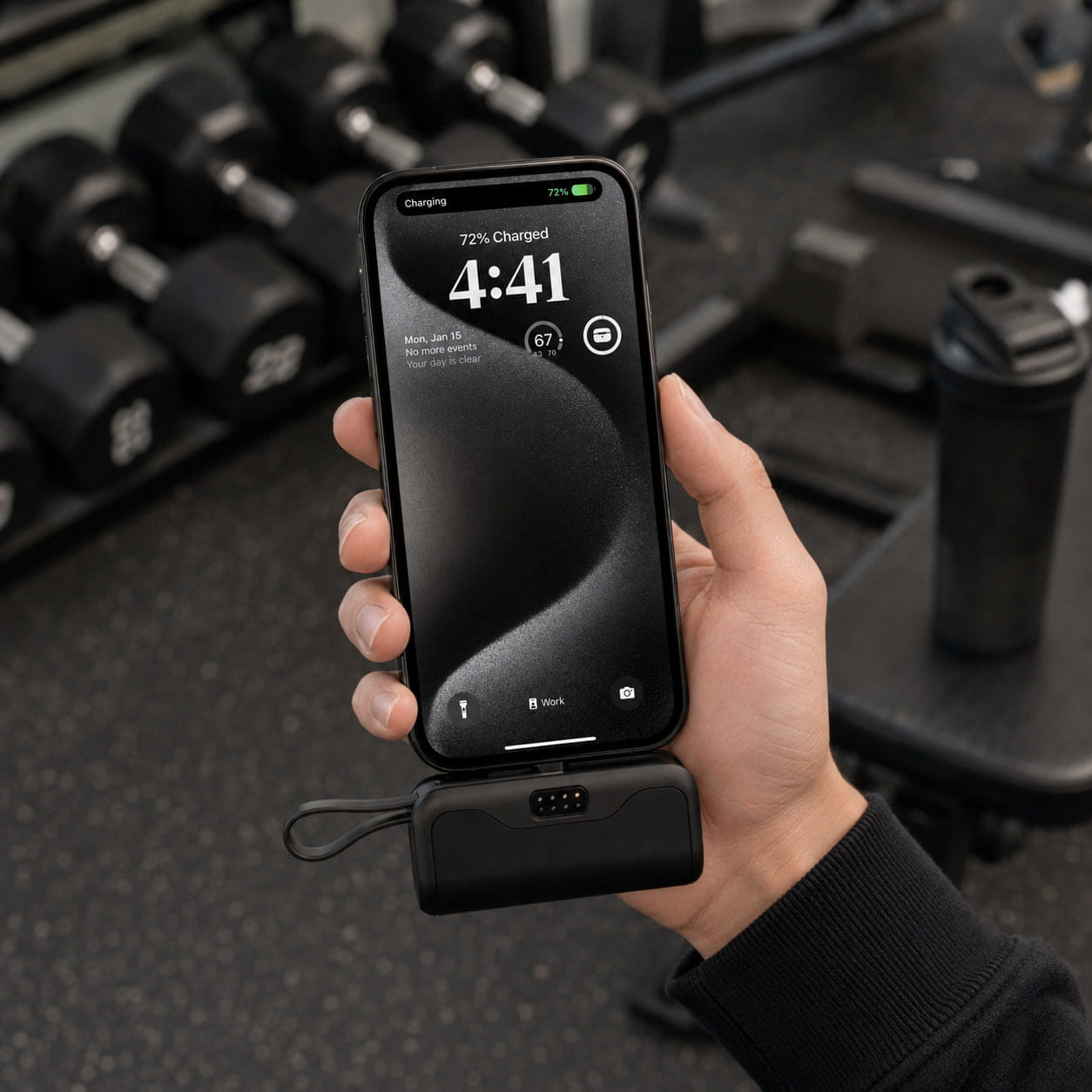 Person holding the black Luminomo Go portable power bank after a workout.