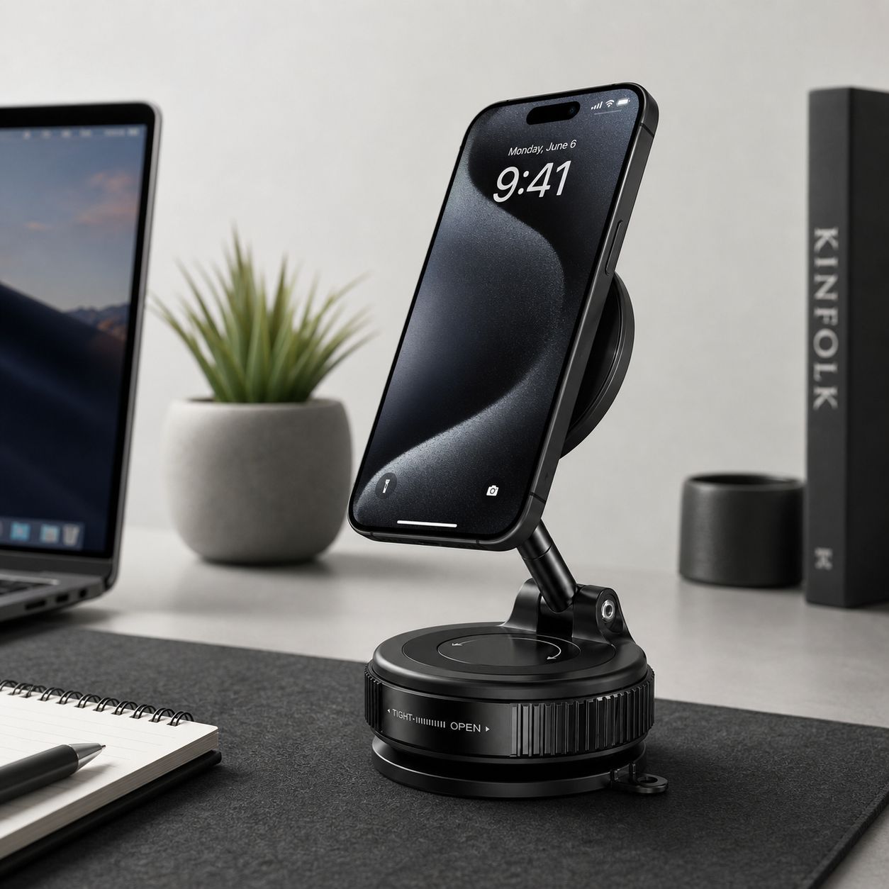 Luminomo Orbit magnetic phone stand holding a smartphone on a modern desk setup beside a laptop and workspace accessories.